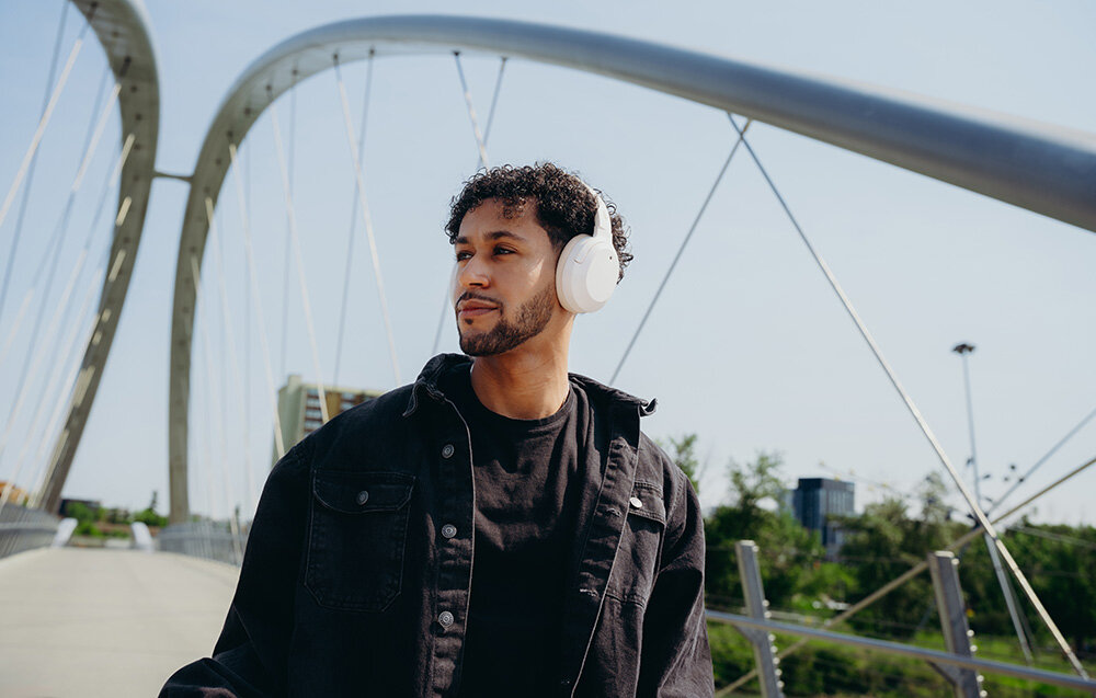 Edifier W820NB Plus V25 bateria 88h szybkie ładowanie 15min 15h ANC, osoba z założonymi słuchawkami nausznymi w plenerze