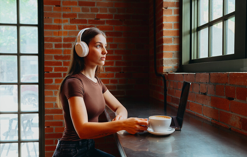 Edifier W820NB Plus V25 aplikacja ConneX Volume Guard przyciski diody sterowanie EQ, osoba z założonymi słuchawkami nausznymi w pomieszczeniu