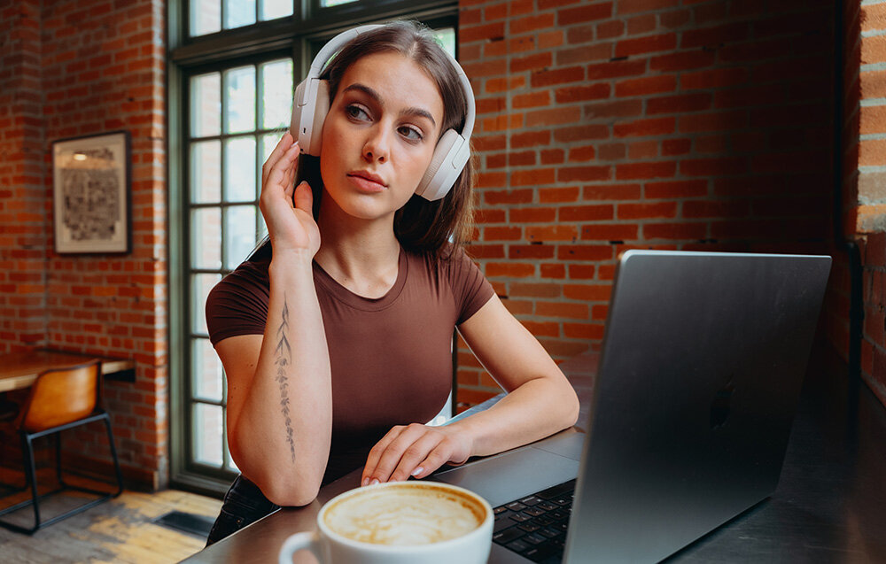 Edifier W820NB Plus V25 komfortowe lekkie słuchawki nauszne regulowany pałąk elegancki design, osoba z założonymi słuchawkami nausznymi w pomieszczeniu