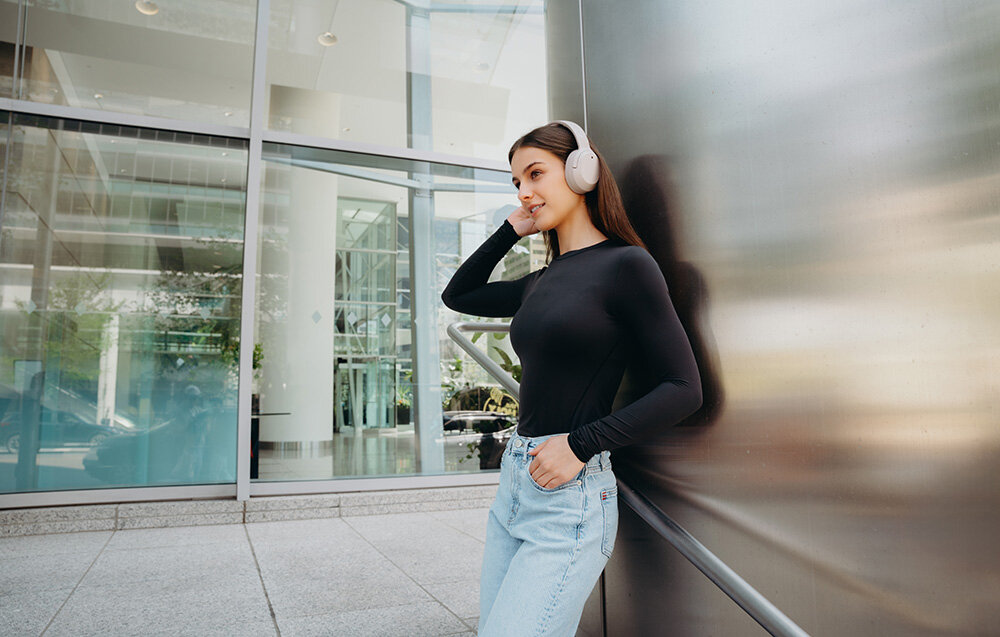 Edifier W820NB Plus V25 ANC -49dB tryby High Medium Ambient Wind Reduction, osoba z założonymi słuchawkami nausznymi w plenerze