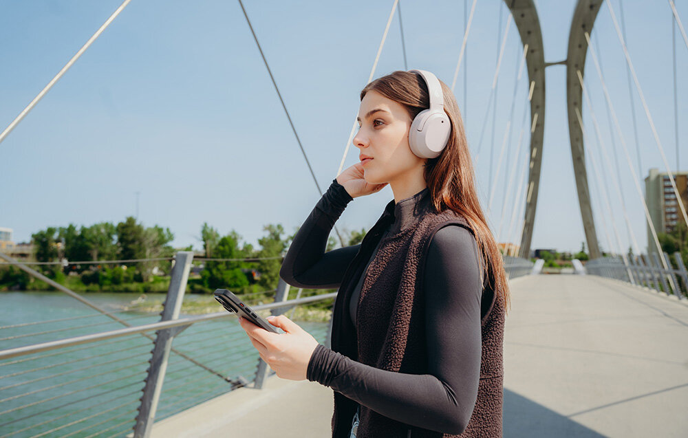 Edifier W820NB Plus V25 Bluetooth 6.1 Multipoint tryb Gaming niskie opóźnienie, osoba z założonymi słuchawkami nausznymi w plenerze