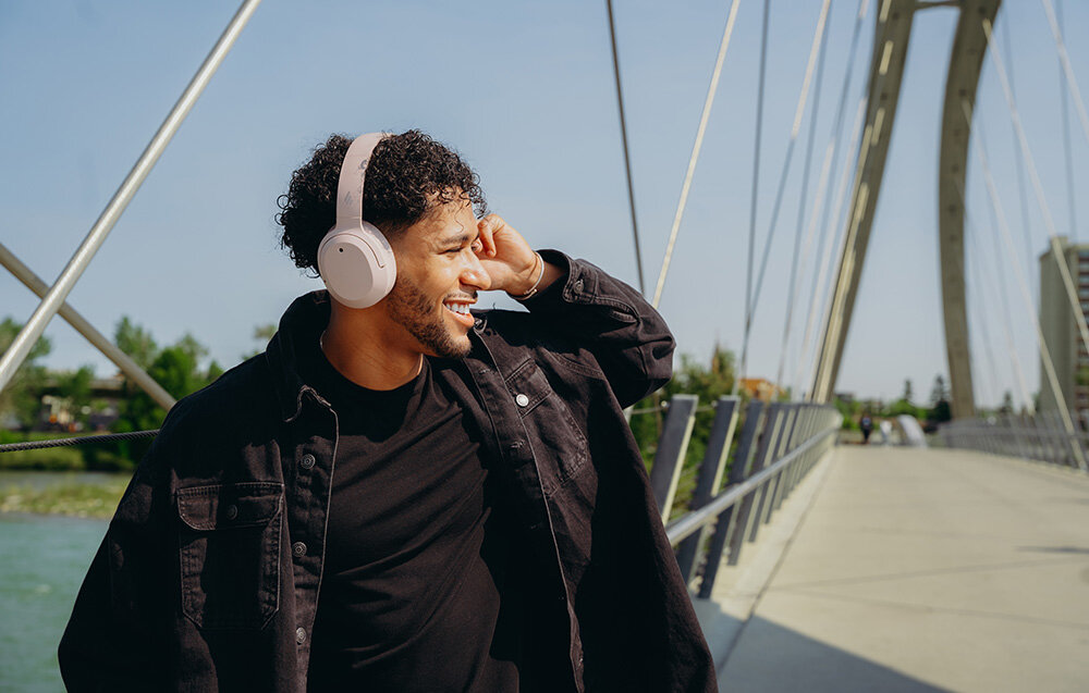 Edifier W820NB Plus V25 mikrofony AI redukcja szumów czysty głos rozmowy telefoniczne wideokonferencje, osoba z założonymi słuchawkami nausznymi w plenerze