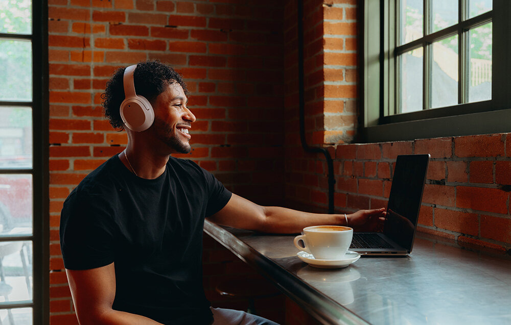 Edifier W820NB Plus V25 bateria 88h szybkie ładowanie 15min 15h ANC, osoba z założonymi słuchawkami nausznymi w pomieszczeniu