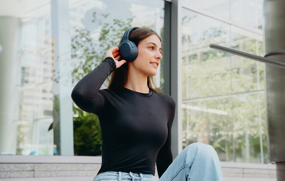 Edifier W820NB Plus V25 słuchawki bezprzewodowe ANC Bluetooth 6.1 LDAC Hi-Res Volume Guard Multipoint, osoba z założonymi słuchawkami nausznymi w plenerze