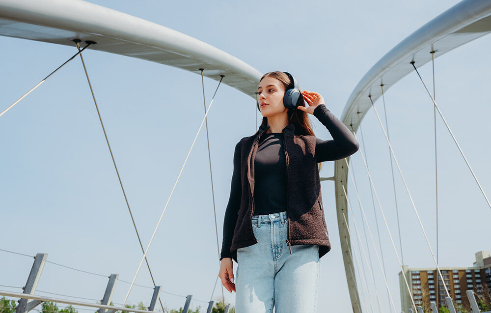 Edifier W820NB Plus V25 ANC -49dB tryby High Medium Ambient Wind Reduction, osoba z założonymi słuchawkami nausznymi w plenerze