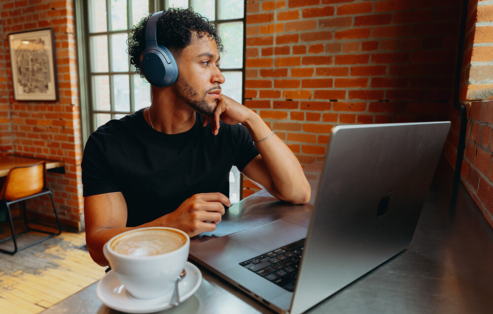 Edifier W820NB Plus V25 LDAC 24bit 96kHz Hi-Res przetworniki tytanowe equalizer Bass Boost Treble Boost, osoba z założonymi słuchawkami nausznymi siedząca przed laptopem