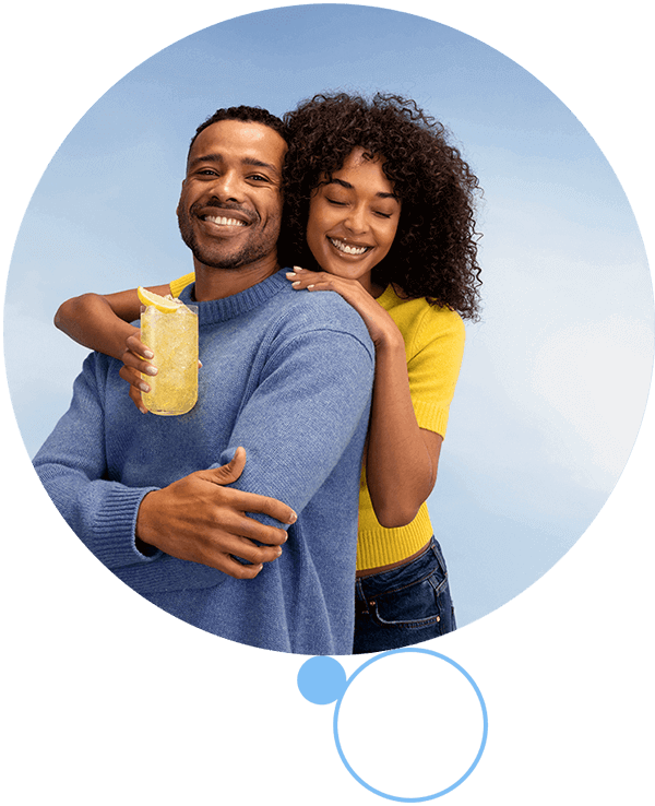 Maszyna SodaStream MIX z mężczyzną nasycającym napój, kobietą trzymającą pomarańczowy koktajl i kieliszkiem wina na blacie