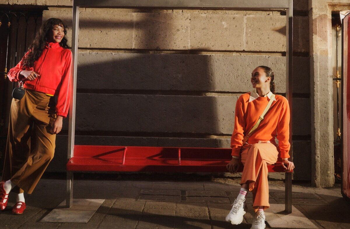 Głośnik mobilny BOSE SoundLink Micro 2nd Gen SimpleSync łączenie z listwami dźwiękowymi i głośnikami Bose, osoba siedząca na przystanku autobusowym oraz osoba opierająca się o przystanek autobusowy