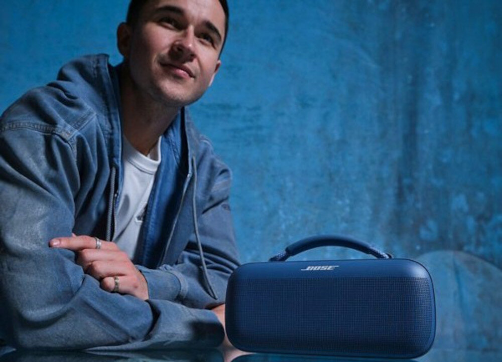 Głośnik mobilny BOSE SoundLink Max podkręca atmosferę, dźwięk stereo i basy do imprezy, głośnik stojący na blacie, osoba opierająca się o blat