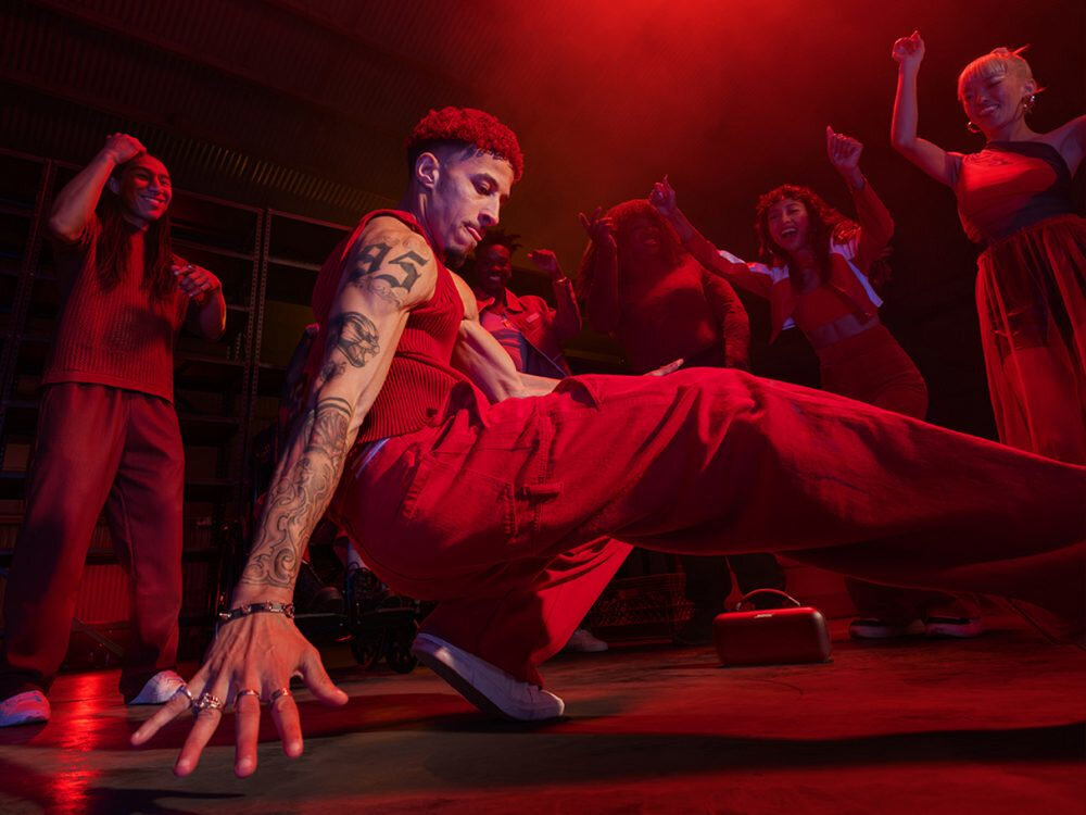 BOSE SoundLink Max głębokie basy dynamiczne brzmienie, głosnik stojący na podłodze przy osobie tańczącej breakdance