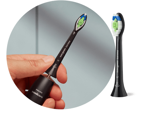 Dłoń trzymająca szczoteczkę z wyjętą końcówką. Obok znajduje się końcówka szczoteczki.