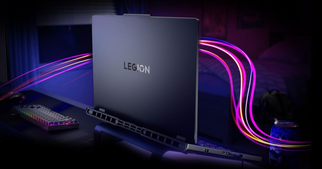 Tylny widok zamkniętego laptopa LENOVO Legion Pro 5 16IAX10 na ciemnym biurku gamingowym, logo Legion na pokrywie z turkusowym podświetleniem, intensywne różowo-fioletowe paski światła RGB wyginające się za laptopem – podświetlenie RGB klawiatury Thunderbolt 4 HDMI 2.1