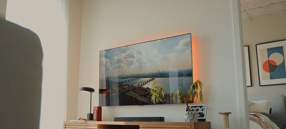Soundbar BOSE Smart Ultra kinowy dźwięk przestrzenny, soundbar stojący na komodzie pod zawieszonym telewizorem