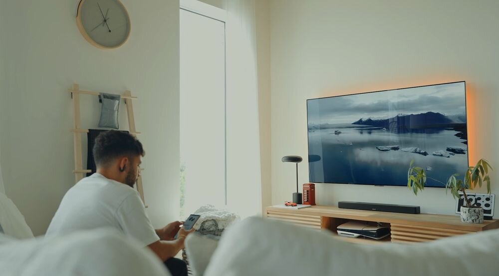 Soundbar BOSE Smart Ultra Personal Surround Sound Bose Ultra Open Earbuds, soundbar stojący na komodzie pod zawieszonym telewizorem