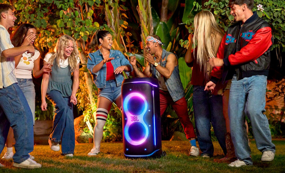 Power audio JBL PartyBox 720 głośniki 9-calowe moc 800W czysty dźwięk basy, power audio stojące na trawniku, osoby bawiące się w rytm muzyki