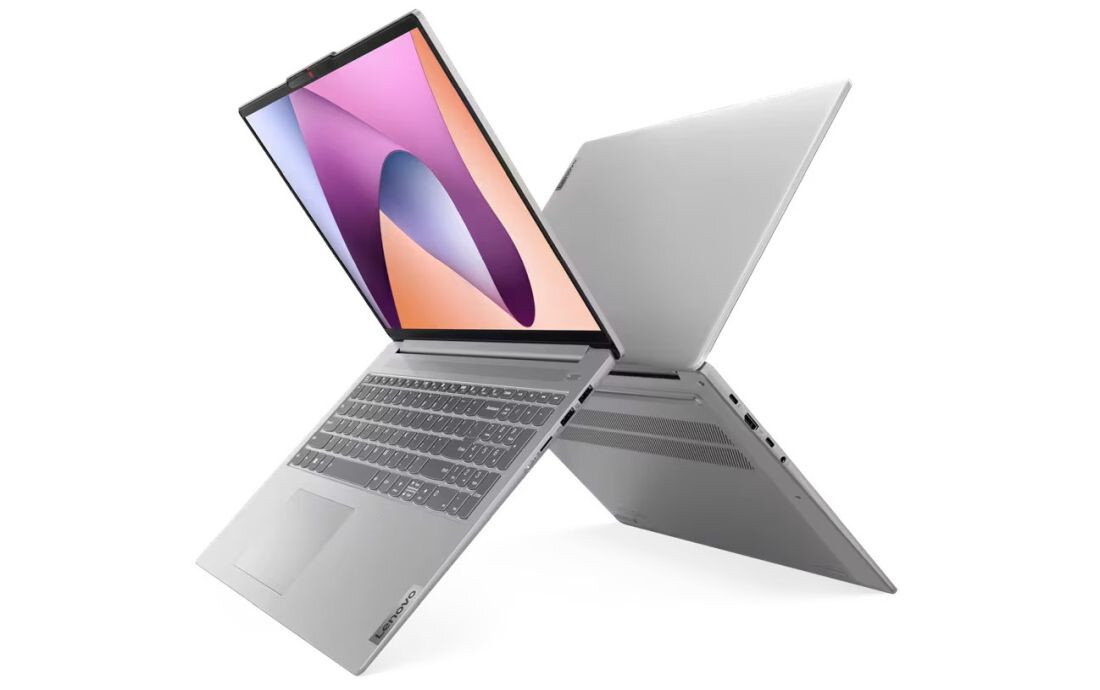 Dwa laptopy w kolorze srebrnym ustawione w kształcie litery X, z widocznymi klawiaturami i ekranami. Na jednym z laptopów widoczny jest kolorowy ekran z abstrakcyjnym wzorem.