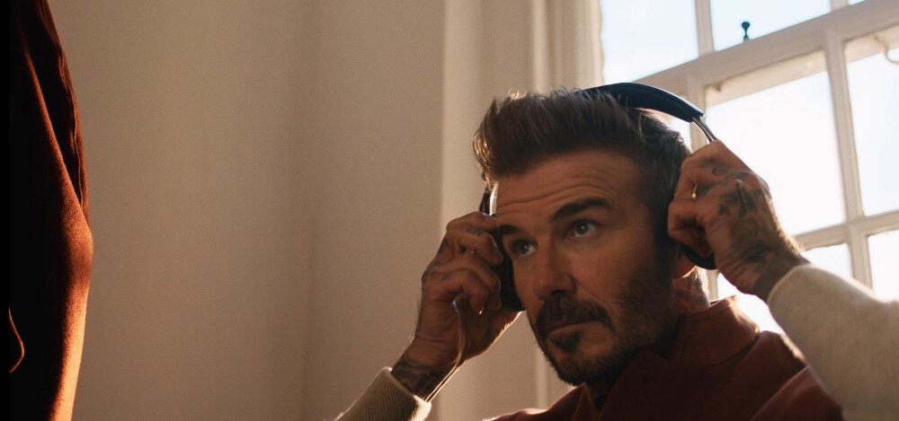 Słuchawki nauszne BOWERS & WILKINS Px8 S2 ANC Onyx Black Warm Stone elegancki luksusowy design, David Beckham z założonymi słuchawkami nausznymi