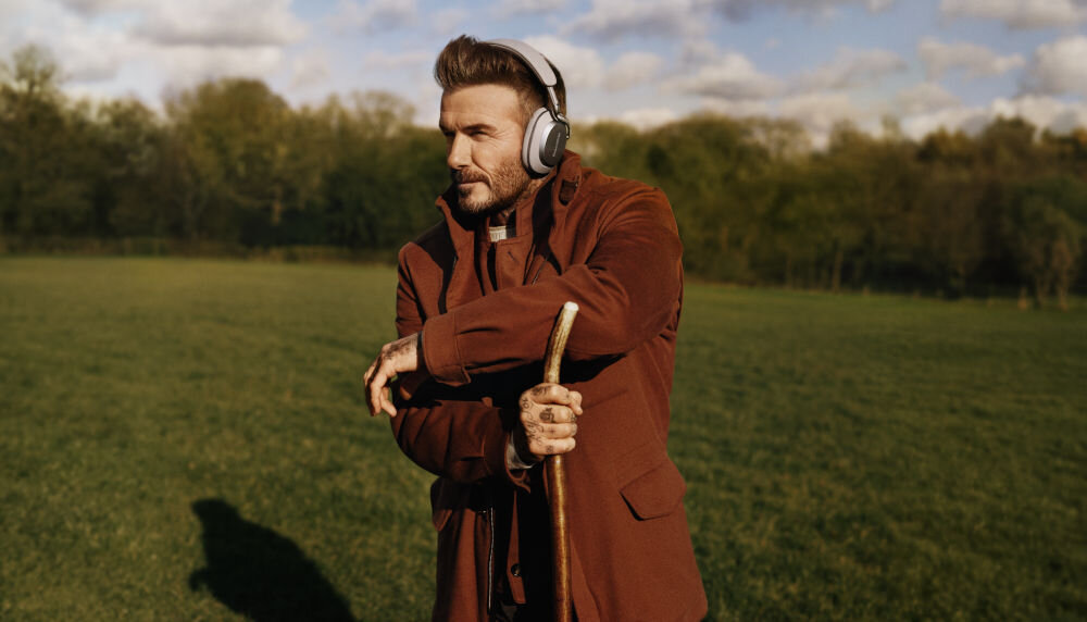 Słuchawki nauszne BOWERS & WILKINS Px8 S2 ANC przetworniki Carbon Cone komfort precyzyjne brzmienie, David Beckham z założonymi słuchawkami nausznymi