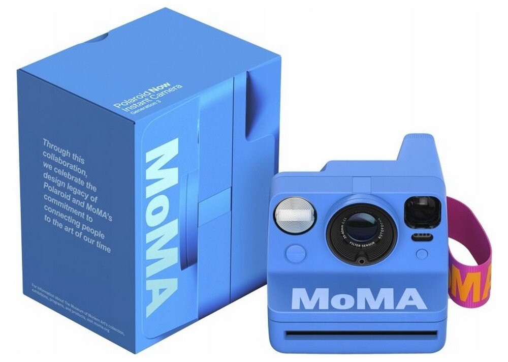 Na obrazie widoczny jest niebieski aparat natychmiastowy z napisem \'MoMA\' oraz pudełko z napisem \'Polaroid Now Instant Camera\'. Na pudełku znajduje się tekst: \'Through this collaboration, we celebrate the design legacy of Polaroid and MoMA’s commitment to connecting people to the art of our time\'.