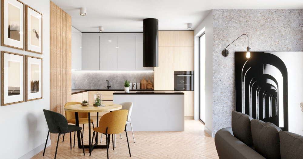 OKAP GLOBALO CYLINDRO ISOLA 39.7 BLACK Zdjęcie przedstawia jasną kuchnię z wyspą, przy której ustawiony jest okrągły stół i cztery różnokolorowe krzesła. Na ścianie wiszą cztery ramki ze zdjęciami, a w tle widać elementy dekoracyjne oraz rośliny. Kuchnia posiada szafki w jasnych barwach, ciemny blat oraz czarny okap nad wyspą. Po prawej stronie znajduje się przestronny salon z szarą kanapą i dużym obrazem na ścianie.