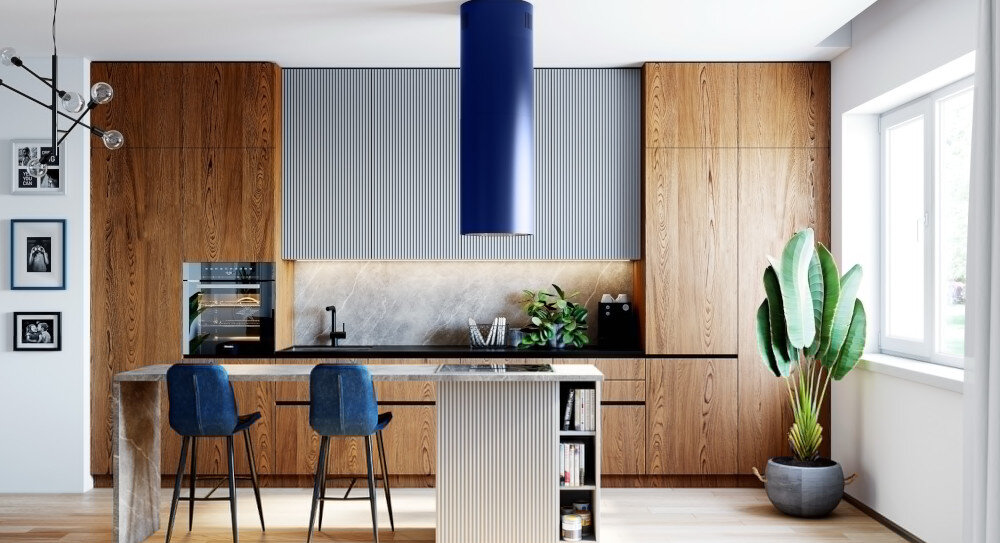 OKAP GLOBALO CYLINDRO ISOLA 39.7 BLUE Zdjęcie przedstawia jasną kuchnię z wyspą, przy której ustawiony jest okrągły stół i cztery różnokolorowe krzesła. Na ścianie wiszą cztery ramki ze zdjęciami, a w tle widać elementy dekoracyjne oraz rośliny. Kuchnia posiada szafki w jasnych barwach, ciemny blat oraz niebieski okap nad wyspą. Po prawej stronie znajduje się przestronny salon z szarą kanapą i dużym obrazem na ścianie.