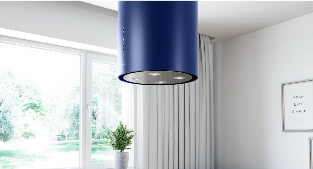 OKAP GLOBALO CYLINDRO ISOLA 39.7 BLUE Zdjęcie przedstawia kuchnię z wyspą wyposażoną w płytę grzewczą. Nad wyspą zamontowany jest okap w kształcie niebieskiej tuby z czterema wbudowanymi lampkami LED. W centralnym miejscu na wyspie stoi roślina w doniczce, a w tle widać eleganckie, połyskujące szafki oraz detale kuchenne. Całość utrzymana jest w jasnej, minimalistycznej aranżacji z kontrastowym niebieskim akcentem wyspowy globalo niebieski stal szlachetna tuba kuchenny sufitowy design premium wyspa cylindryczny elegancki kuchnia agd wydajny dekoracyjny