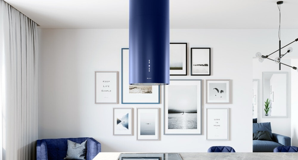 OKAP GLOBALO CYLINDRO ISOLA 39.7 BLUE Zdjęcie przedstawia detal okapu w kształcie niebieskiej tuby, zawieszonego nad wyspą kuchenną. W tle widoczna jest jasna ściana z pionowymi drewnianymi listwami i cztery obrazy w ramkach. Poniżej częściowo widać drewniany stół z krzesłami oraz elementy blatu kuchennego z doniczką. Kompozycja podkreśla elegancki design oraz wykończenie wnętrza czyste powietrze wydajność 742 m3/h usuwanie pary tłuszczu zapachów tryb wyciąg tryb pochłaniacz filtr aluminiowy filtr węglowy wentylacja świeżość kuchnia okap skuteczny