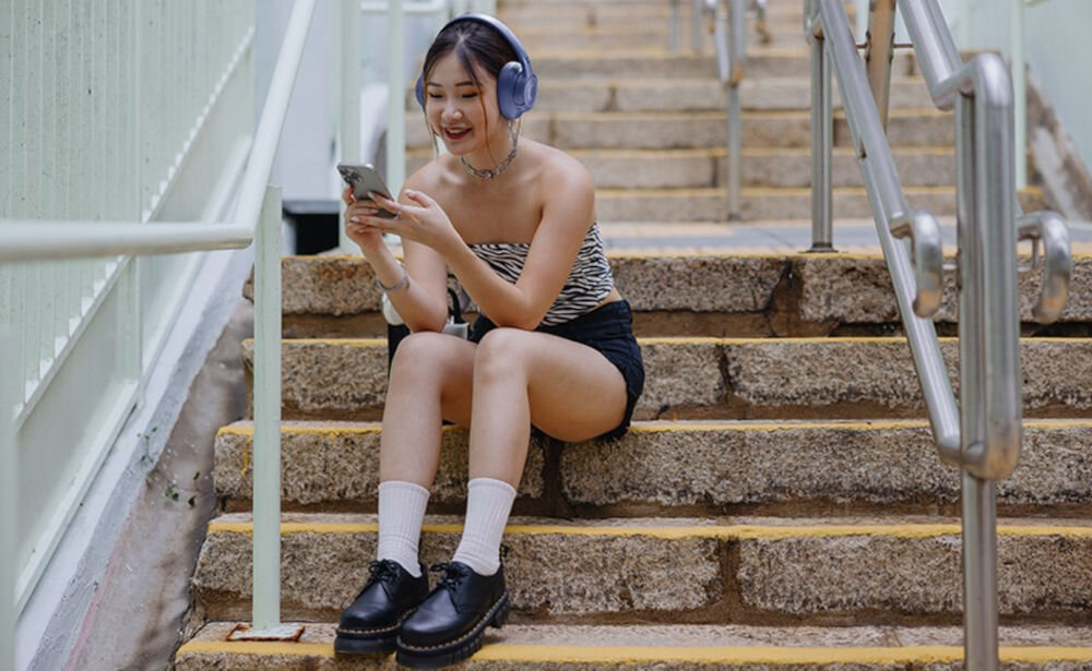 Słuchawki JBL Tune 730BT - Brzmienie, które inspiruje, osoba z założonymi słuchawkami siedząca na schodach