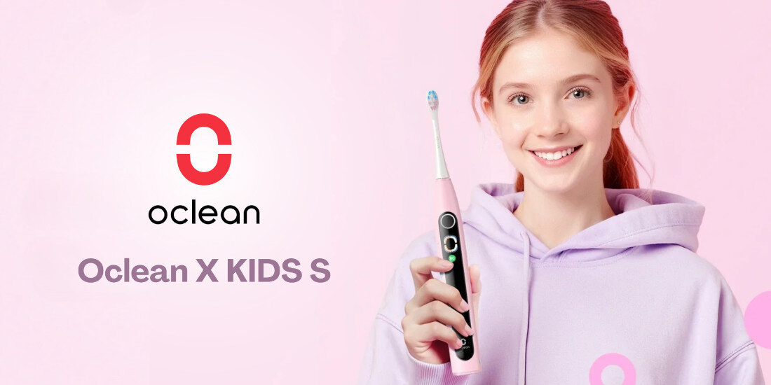 Na różowym tle widoczna jest szczoteczka soniczna w kolorze różowym, trzymana przez osobę w fioletowej bluzie. Obok znajduje się logo \'oclean\' oraz napis \'Oclean X KIDS S\'.