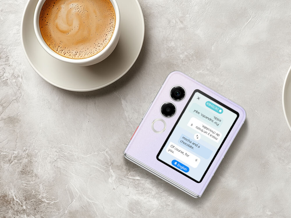 Smartfon NUBIA Flip 2 5G 8/256GB 6.9 120Hz Czarny procesor Dimensity 7300X 5G RAM 24 GB bateria 4325 mAh ładowanie 33W dźwięk DTS X Ultra - Złożony smartfon Nubia Flip w kolorze lawendowym, leżący na marmurowym lub betonowym blacie, obok filiżanki kawy. Na zewnętrznym ekranie telefonu wyświetlana jest aplikacja tłumacza z tekstem w języku angielskim i hiszpańskim, od góry (tłumaczenie w czasie rzeczywistym).