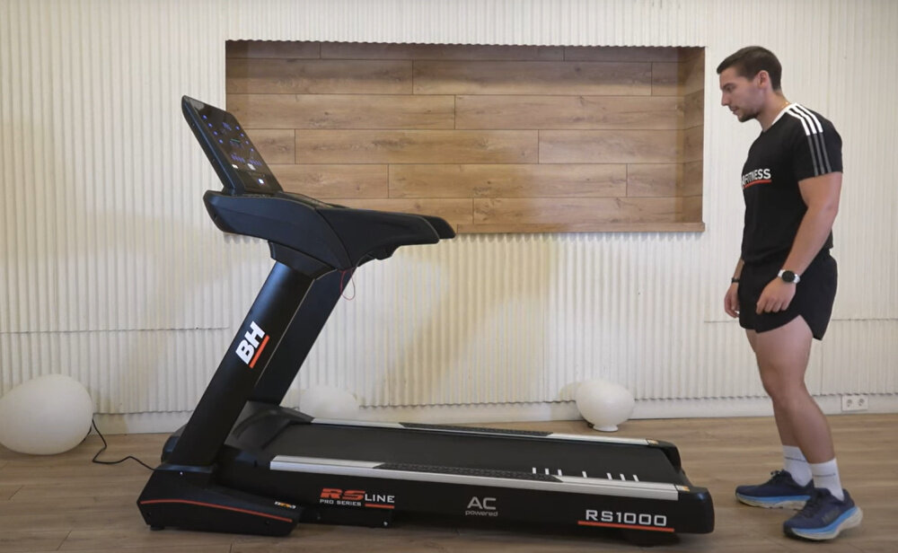 Bieżnia elektryczna BH FITNESS RS1000 2574W 22km-h osoba stoi przed bieżnią w pomieszczeniu trening cardio w domu sprzęt do intensywnych treningów aktywny tryb życia dbanie o zdrowie