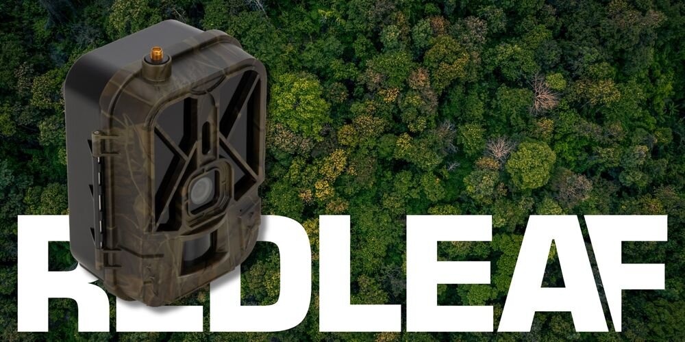 Na tle gęstego lasu widoczna jest fotopułapka w kolorze maskującym. Na dole obrazu znajduje się duży, biały napis \'REDLEAF\'.