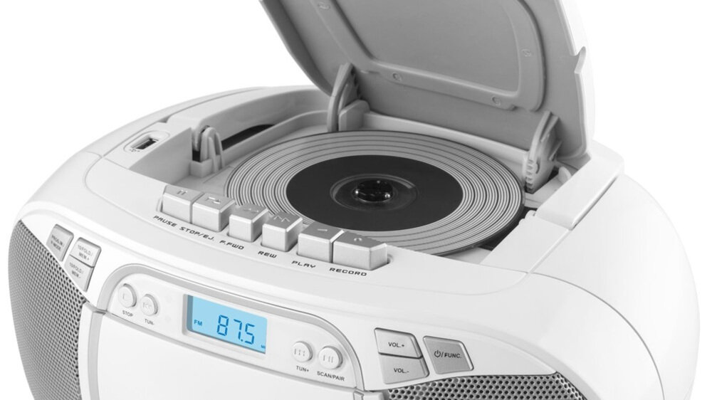 Biały radioodtwarzacz z otwartą pokrywą na płyty CD, wyświetlaczem LCD pokazującym \'87.5\' oraz przyciskami funkcyjnymi. Widoczne są przyciski do regulacji głośności i zmiany stacji radiowych.