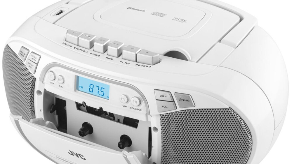 Biały radioodtwarzacz z wyświetlaczem pokazującym częstotliwość 87.5 oraz otwartą kieszenią na kasety. Na górze widoczne są przyciski sterujące, a po bokach głośniki i logo JVC.