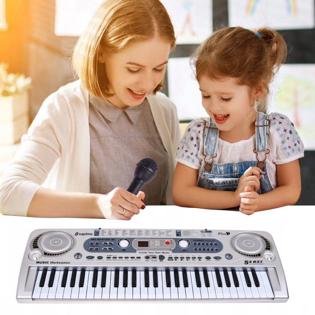 Na zdjęciu znajduje się klawiatura edukacyjna Suprimo 824 USB z mikrofonem i pulpitem do nut, z widocznymi napisami \'Suprimo\', \'MUSIC Workstation\', \'Create Your Own Music\', \'54 KEY\'. W tle widać dwie osoby, z których jedna trzyma mikrofon.