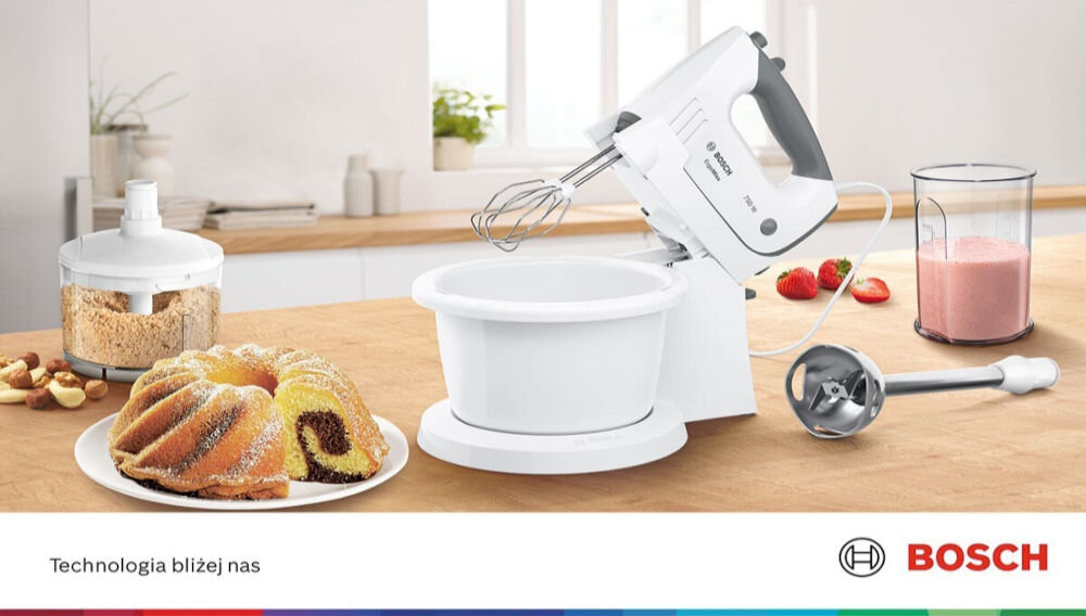Na blacie kuchennym znajduje się biały mikser z misą, obok niego leży blender ręczny i pojemnik z różowym napojem. Na pierwszym planie widoczna jest babka na talerzu, a w tle logo BOSCH i napis \'Technologia bliżej nas\'.