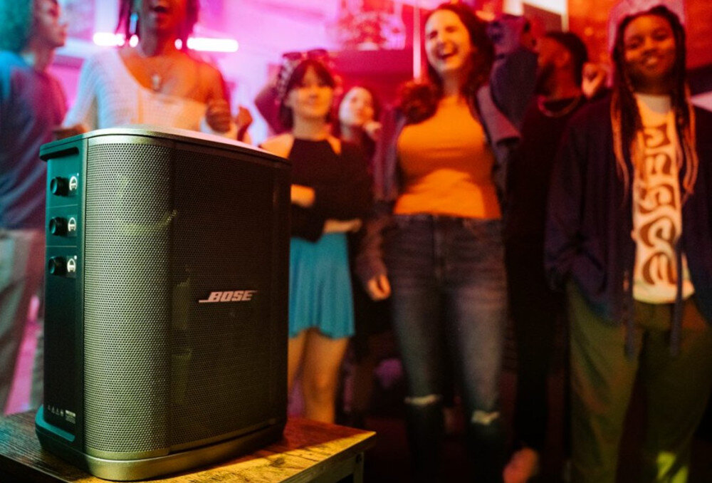 Power Audio BOSE S1 Pro+ 3-kanałowy mikser mikrofon instrument Bluetooth, urządzenie stojące na stoliku, osoby bawiące się w rytm muzyki