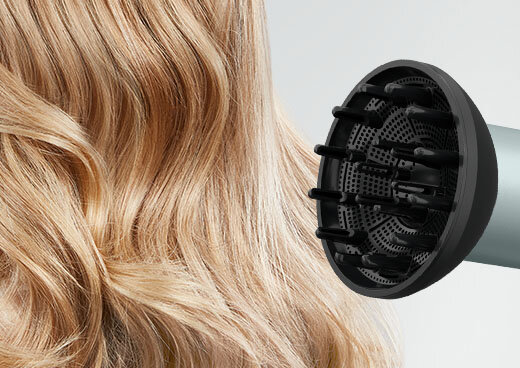 Zbliżenie na dyfuzor suszarki ROWENTA HY7120, obok zbliżenie na blond włosy.