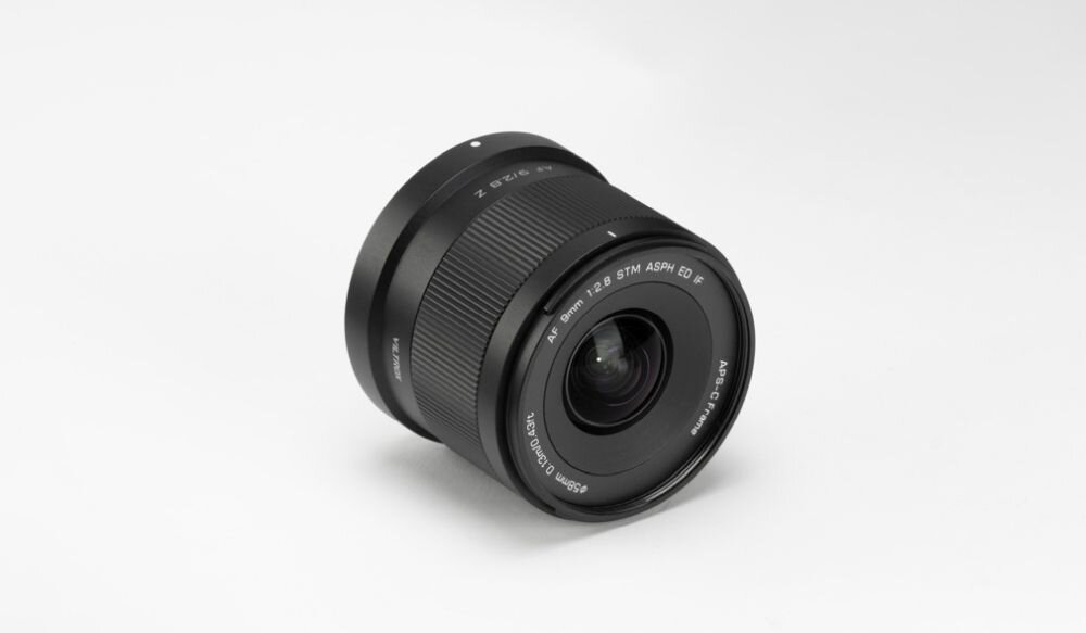 Czarny obiektyw z widocznymi napisami: \'9mm f/2.8 STM ASPH ED IF\' oraz \'APS-C 62mm Ø52\'.
