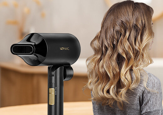 Suszarka, obok kobieta z długimi włosami zwrócona tyłem.