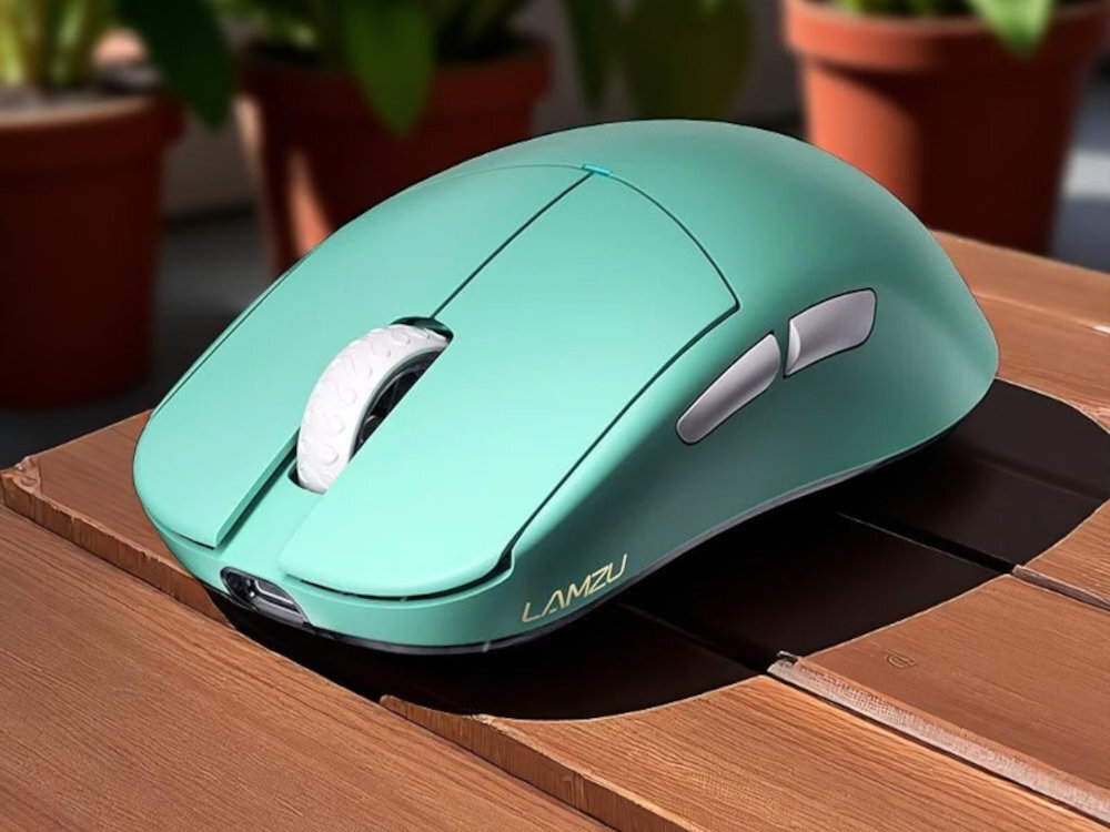 Na drewnianej powierzchni leży niebieska mysz komputerowa z białym kółkiem przewijania i dwoma przyciskami bocznymi. Na myszy widoczne jest logo \'LAMZU\'.