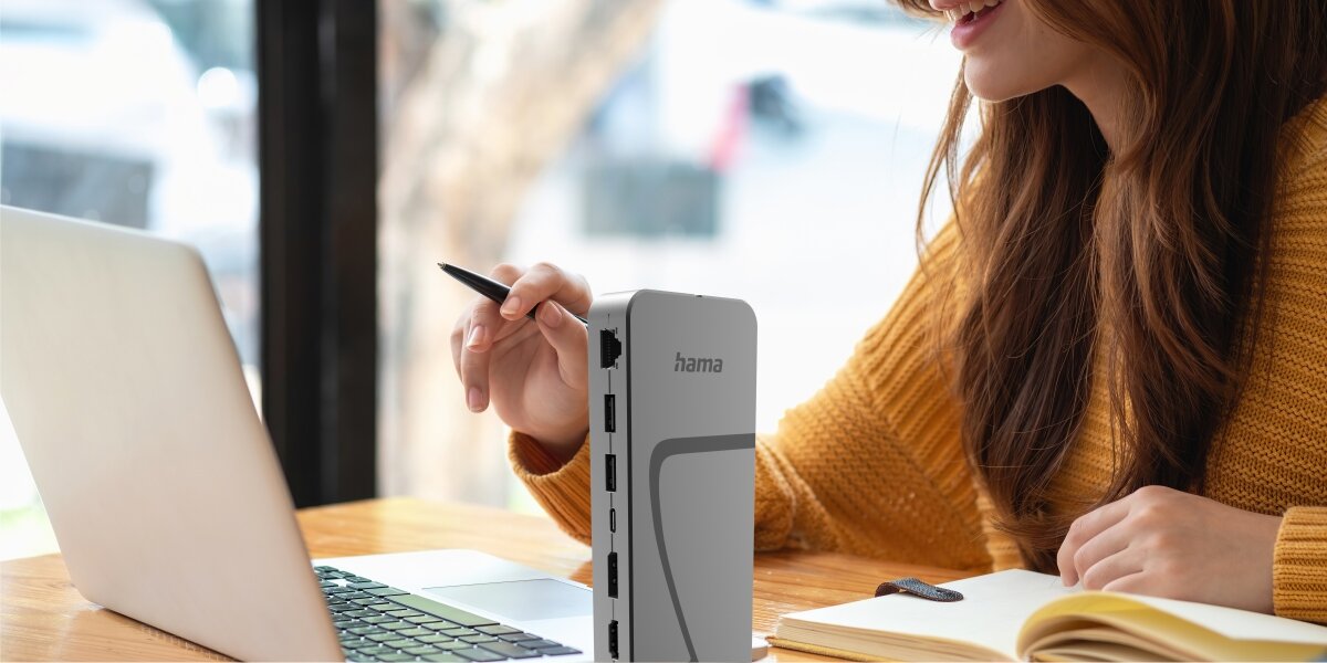 Stacja dokująca HAMA Connect2Office Speed USB Typu C, Pasywna Stacja dokująca Hama USB-C ustawiona pionowo na biurku obok laptopa, prezentująca dostępne porty boczne.