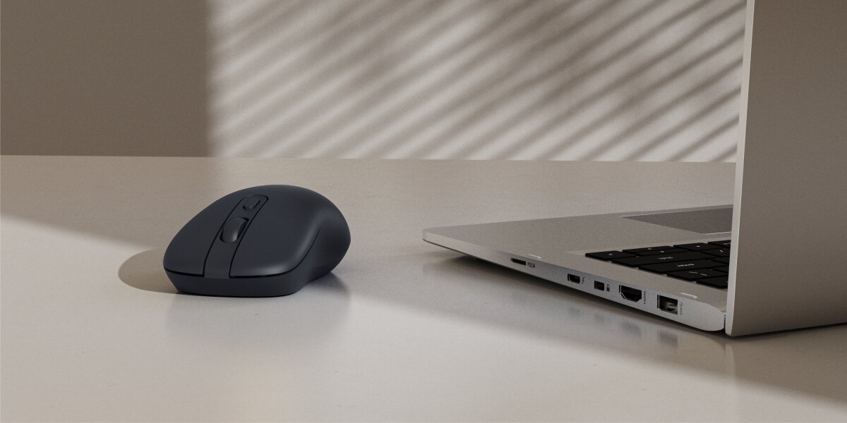 Mysz HAMA WM-200 Czarny Mysz bezprzewodowa Hama w kolorze antracytowym umieszczona obok laptopa na jasnym biurku.