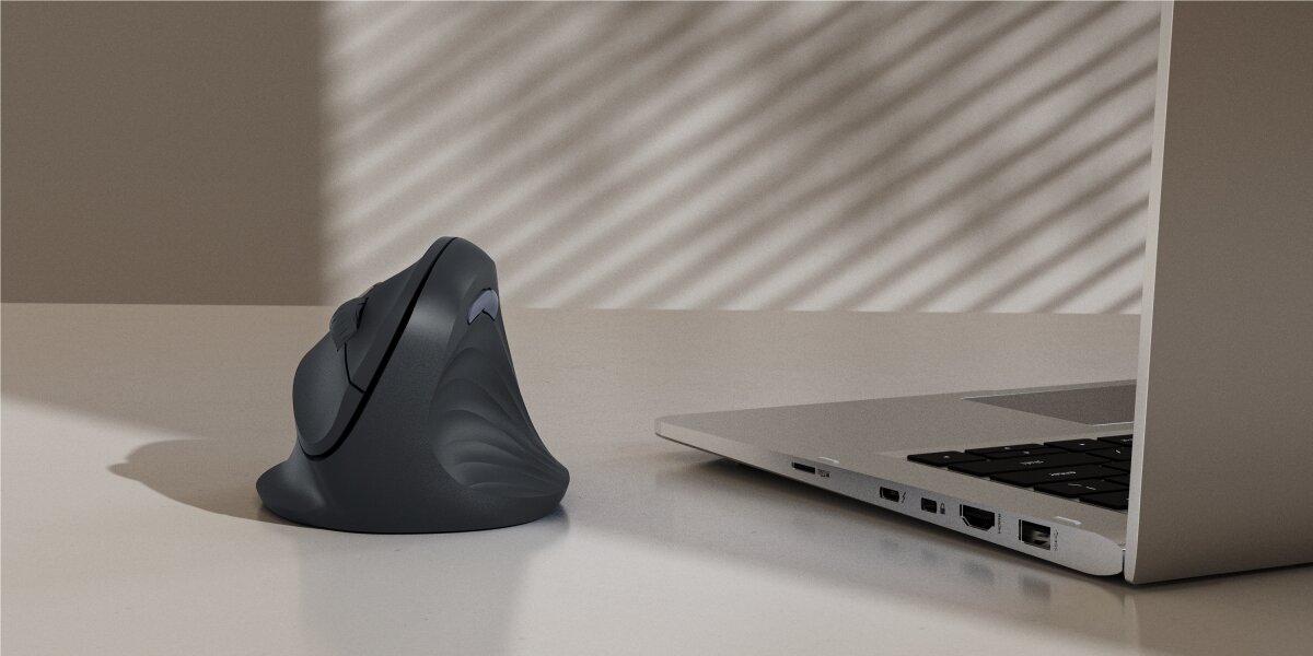 Mysz HAMA EWM-500 Czarny Pionowa mysz ergonomiczna Hama w kolorze antracytowym ustawiona na biurku obok nowoczesnego laptopa.