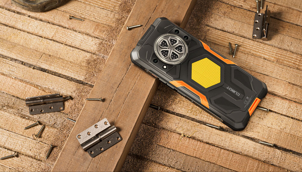 Smartfon CUBOT KING KONG Power 5 16/128GB 6.88 120Hz Czarny Pancerny smartfon Cubot leży tyłem na drewnianych deskach w otoczeniu śrub i zawiasów, co sugeruje jego trwałość w środowisku pracy/budowy