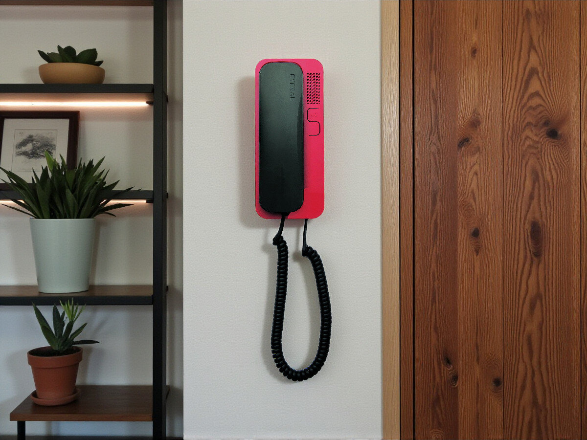 Unifon CYFRAL Smart-D Czarno-czerwony, cyfrowy, przyciski, montaż, design, Unifon Smart-D czarno-czerwony zawieszony na ścianie przy półkach z roślinami, wnętrze z drewnianymi drzwiami.