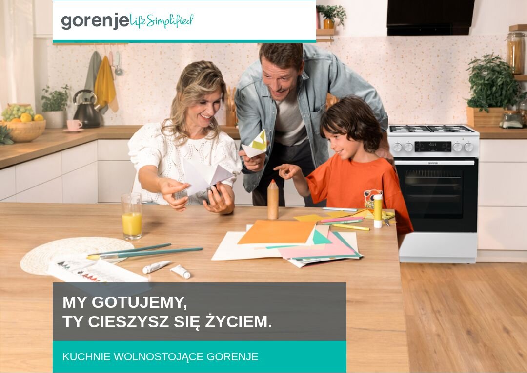 KUCHNIA GORENJE GKS5C72WF Rodzina złożona z dwóch dorosłych i dziecka spędza czas przy kuchennym stole, wycinając kolorowe elementy z papieru, w tle widoczna jest zabudowa kuchenna z kuchnią wolnostojącą Gorenje, a u dołu znajduje się napis „MY GOTUJEMY, TY CIESZYSZ SIĘ ŻYCIEM. KUCHNIE WOLNOSTOJĄCE GORENJE”