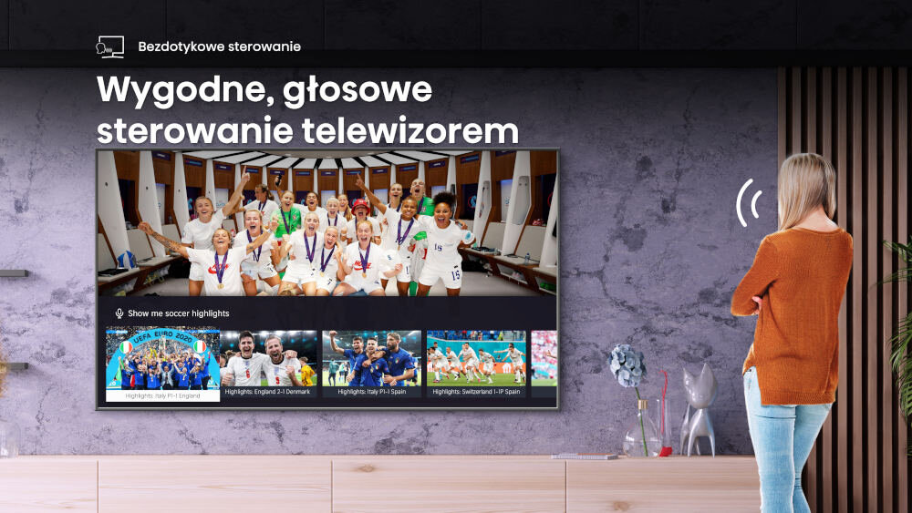 Na ścianie wisi telewizor, na którym wyświetlany jest obraz drużyny sportowej w szatni. Obok znajduje się napis: \'Wygodne, głosowe sterowanie telewizorem\'.