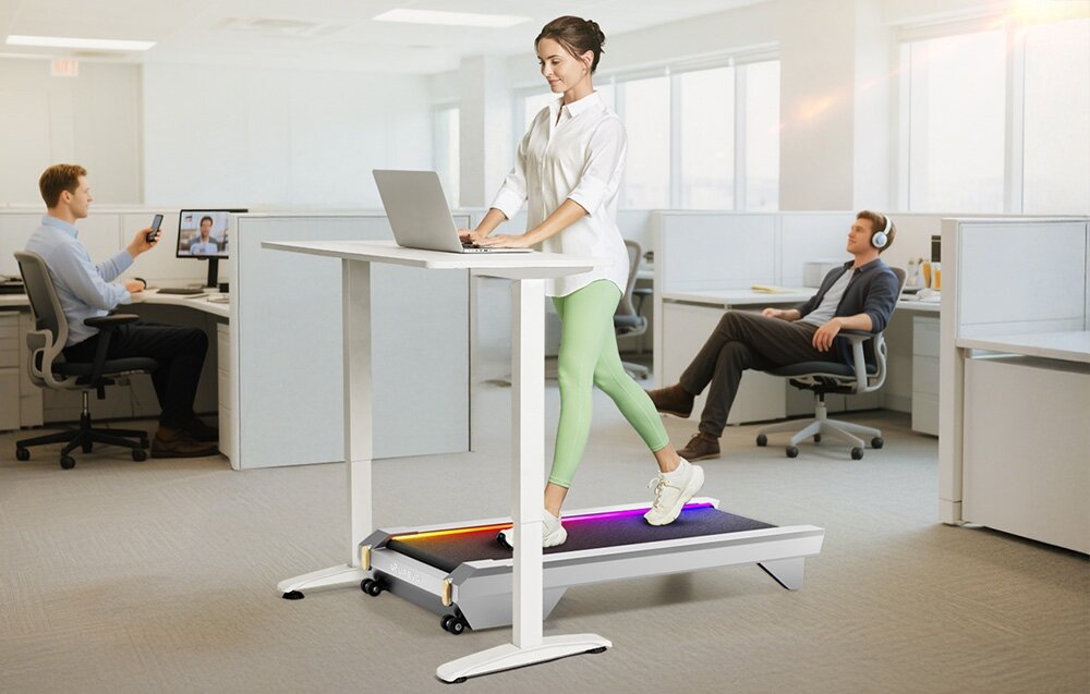 Bieżnia elektryczna UREVO CyberPad for Office 550W 6 km-h pomieszczenie biuro osoba pracuje przy biurku chodząc na bieżni spacer przy biurku walking pad trening