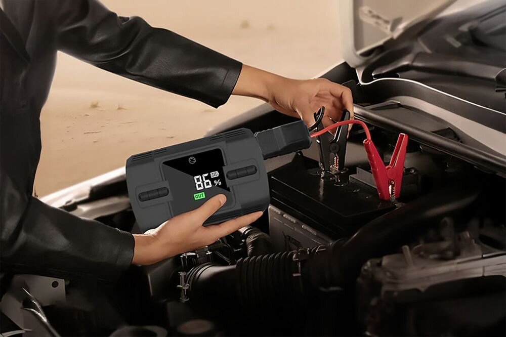 Manta MAJS001AP jump starter 1200A rozruch silnika 12V benzyna 6.0L diesel 3.0L, osoba trzymająca urządzenie podłączone do akumulatora